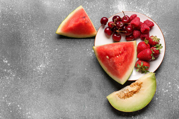 Fototapeta na wymiar Plate with pieces of fresh watermelon and different berries on grey background