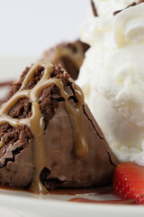 triangular piece of brownie accompanied by ice cream in the foreground