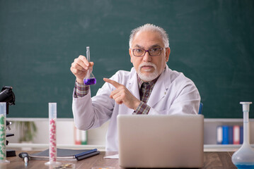 Old male teacher chemist sitting in the classroom