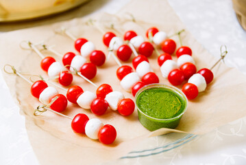 Cherry tomatoes and mini mozzarella cheese balls on skewers with pesto sauce