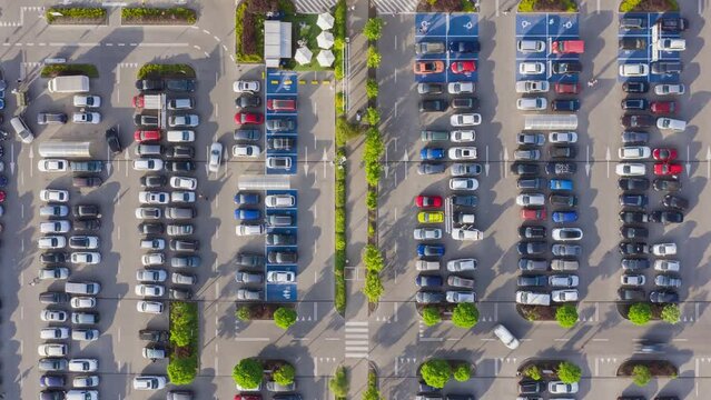 Aerial time-lapse parking near big shopping mall in city, car traffic, parking overhead drone top down view, daylight summer season, timelapse of moving cars, busy supermarket car park