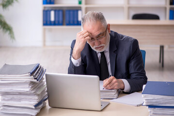 Naklejka premium Old male employee and too much work at workplace