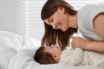 Happy mother with her little baby on bed at home