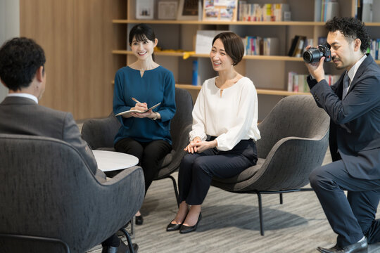 会社で社長への企業インタビューの取材の様子　カメラマンと記者複数