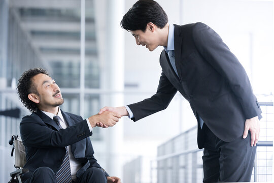 Businessman shaking hands Businessman in wheelchair and greeter