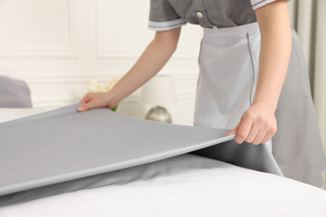 Maid making bed in hotel room, closeup