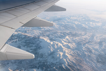 Fototapeta na wymiar aerial snow covered mountain ridge peaks in alps at winter, above view airplane wing