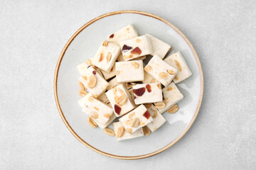 Pieces of delicious nutty nougat on light gray table, top view