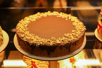 Delicious wafer cake with condensed milk, chocolate and nuts on counter in bakery shop, closeup