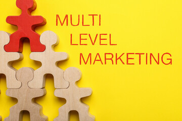 Multi-level marketing. Pyramid of wooden human figures with red one at top showing hierarchy on...