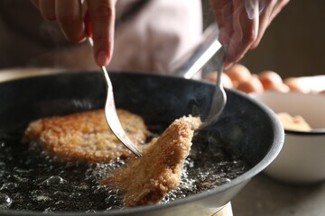 Woman cooking schnitzels in frying pan, closeup