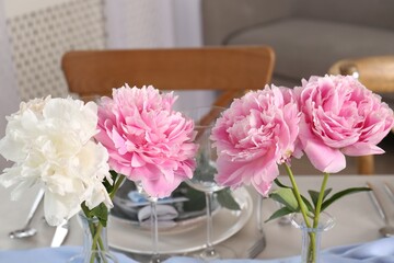 Beautiful table setting. Peonies near plate and cutlery on table indoors