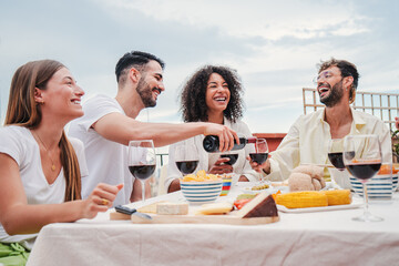 Handsome man fill the wineglass of his brother at lunch or dinner party. Caucasian guy serve the...