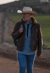 Adult man in cowboy hat walking on dirt road