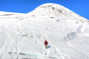 Photo of a person standing in the snow near the majestic volcano Osorno in Patagonia, Chile