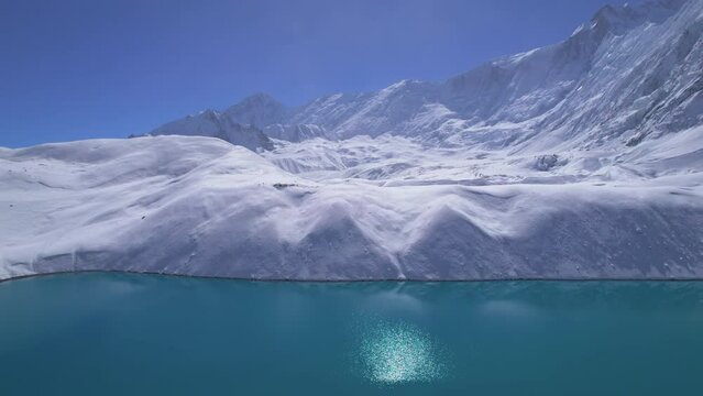Aerial birds eye view fly over Tilicho lake and group of trekkers on trek viewpoint. Nepal. Manang. Himalayas mountain alpine lakes. Trekking Tours and travel in Nepal concept