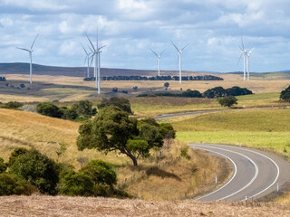 Landscape view wind turbines in a valley with a road winding through