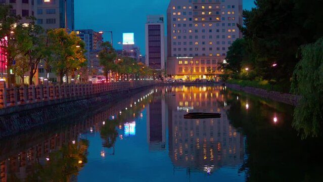 Ambulance with lights flashing drives by city buildings and moat water