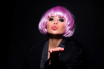 Beautiful air kiss of beauty model, fashionable pink wigs. Photo of young beautiful woman with pink wig isolated on black background.