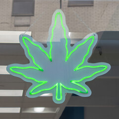 neon green sign of a marijuana leaf in the window of a legal pot dispensary