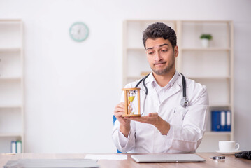 Young male doctor in time management concept