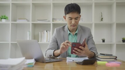 Businessman working in office at desk with financial graph document and laptop Freelance manager holding smartphone using chat messenger app. Career VIDEO 4k - Powered by Adobe