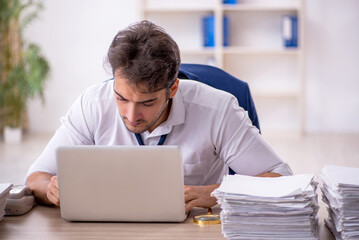 Young male employee and too much work in the office