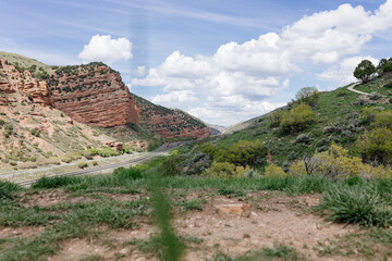 Beautiful landscape with red mountains, highway and blue sky on a sunny day. Panorama taken from a bird's eye view. American landscape.