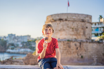Boy tourist eating turkish ice cream on background of Hidirlik Tower in Antalya against the...