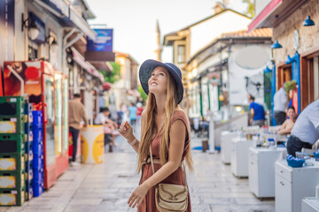 Fototapeta na wymiar Happy woman tourist on background of old street of Antalya. female tourist traveler discover interesting places and popular attractions and walks in the old city Kalechi of Antalya, Turkey. Turkiye