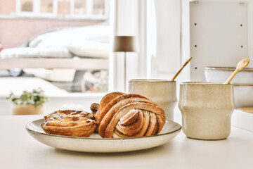 some pastries on a plate with a cup and spoon in the photo is blurry, but it's not clear