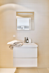 a bathroom with a sink, mirror and towel on the counter top in front of the wall is light beige
