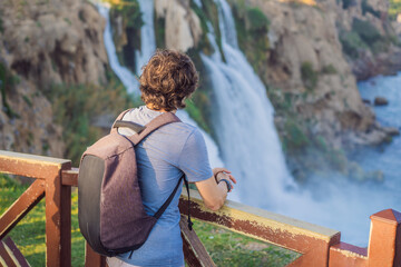 Man tourist on the background of Duden waterfall in Antalya. Famous places of Turkey. Lower Duden Falls drop off a rocky cliff falling from about 40 m into the Mediterranean Sea in amazing water