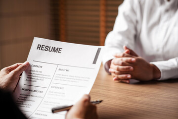 Image of employer or recruiter holding reading a resume during about colloquy his profile of candidate.