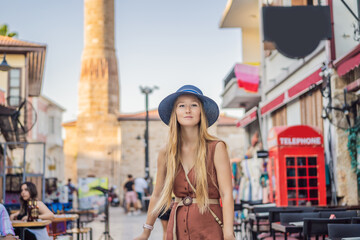 Happy woman tourist on background of old street of Antalya. female tourist traveler discover...