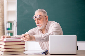 Old male teacher sitting in the classroom