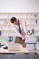 Young male employee unhappy with excessive work in the office