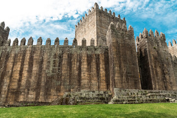 Fototapeta na wymiar Guimaraes, Portugal. April 14, 2022: Walls and structures of Guimarães castle with blue sky.