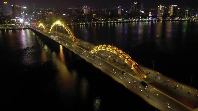 Amazing colorful aerial of iconic Dragon Bridge Cau Rong, traffic and city skyline at night in Danang, Vietnam.