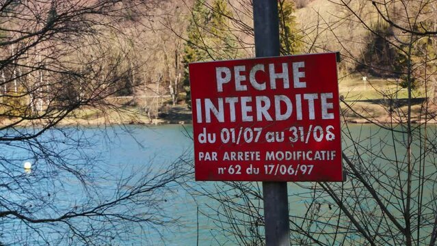 "No fishing" sign in french language. Lake in the background.
