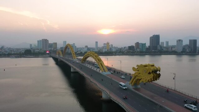 Colorful aerial of Dragon Bridge Cau Rong, traffic and city skyline during sunset in Danang, Vietnam.