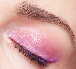 Closeup macro shot of closed human female eye. Woman with perfect skin and pink eyes shadows