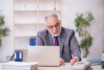 Obraz premium Old male employee working in the office