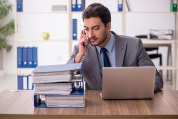 Naklejka premium Young male employee and too much work in the office
