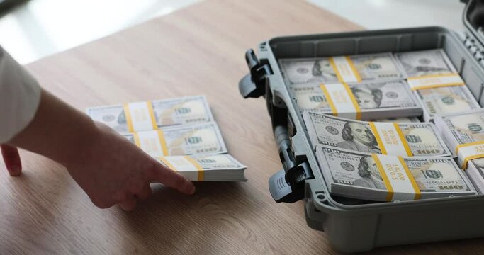 A woman takes out packs of dollars from a suitcase, a close-up. Concept large expenses, cash loss