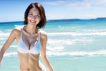 ビーチでビキニを着てカメラ目線で笑顔の日本人女性  - obrazy, fototapety, plakaty