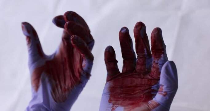 Hands in blue gloves are stained with blood, close-up. Medical error, surgery. Trembling in the hands, slowmotion