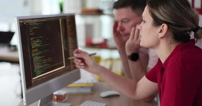 A woman and a man are looking at the code on the computer screen, close-up. Testing a software application