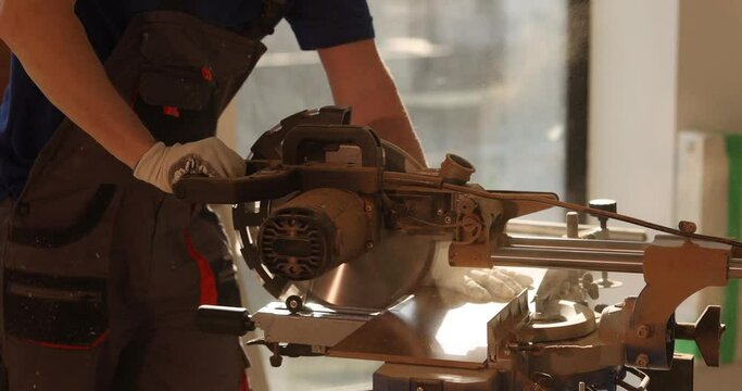Carpenter cuts a wooden laminate on a cutter with a saw, a close-up. Professional work with wood