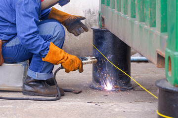 Fototapeta na wymiar Welder is welding metal bollard to use for support foundation of the old container that have been renovated to outdoor office or storage room